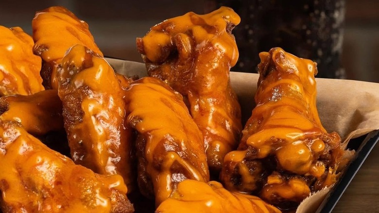 Pile of saucy buffalo chicken wings on paper