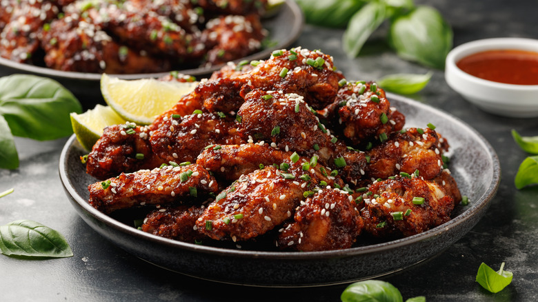 Plate of Korean chicken wings with seasonings next to lime wedges and sauce