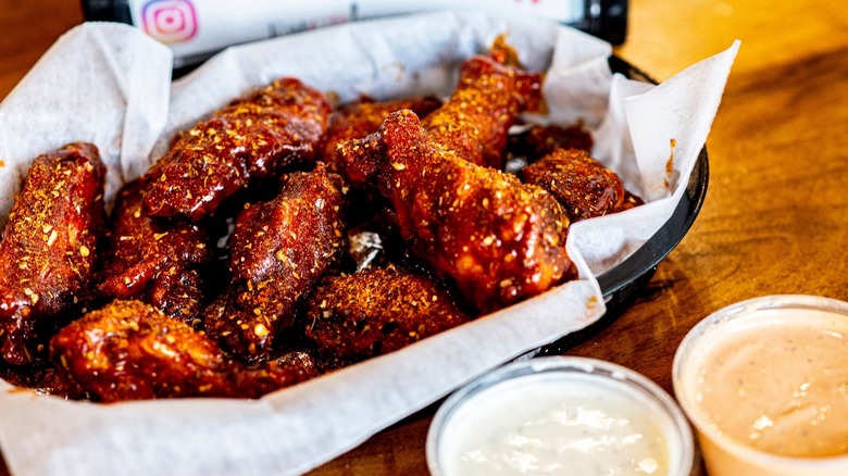 Basket of seasoned wings next to two sauces