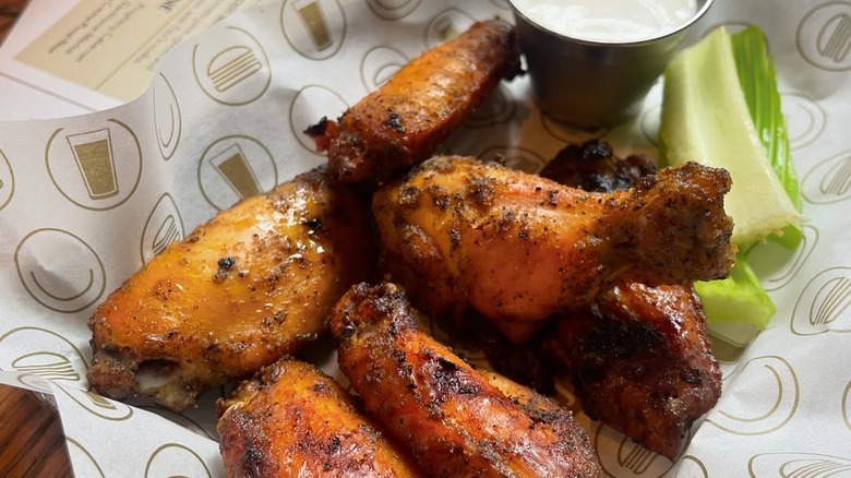 Basket of chicken wings next to ranch and celery sticks