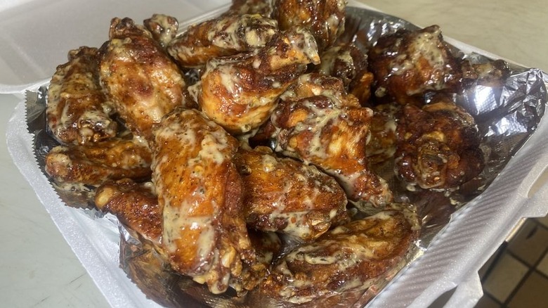 Styrofoam container of saucy wings with aluminum foil
