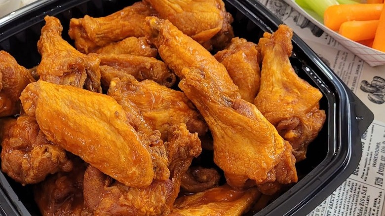 Black plastic container full of buffalo wings