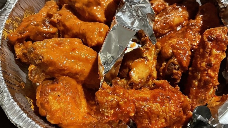 Aluminum plate with two different types of saucy chicken wings