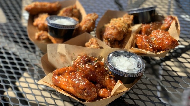 3 paper containers of different types of chicken wings with sauces