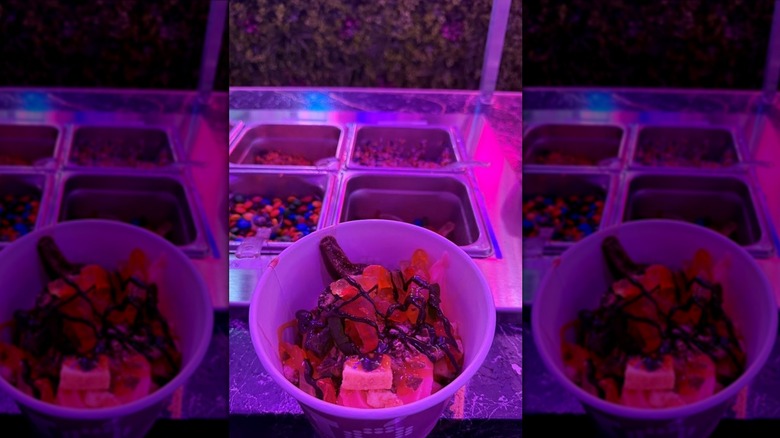 neon lit cup of froyo with tons of candy and chocolate drizzle on top