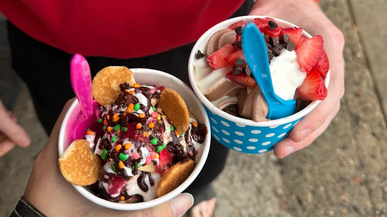 two cups of froyo with tons of different toppings like cookies, fruit, and candy