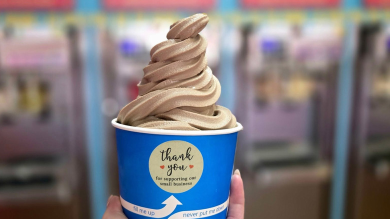 hand holding a blue cup of chocolate swirled froyo