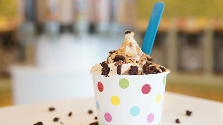 polka dot cup of frozen yogurt with cookie crumbles and a blue spoon