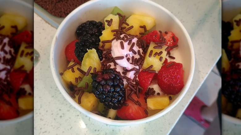 cup of pink froyo with chocolate sprinkles and a variety of fresh fruit chunks
