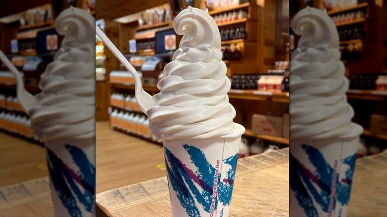 tall white swirl of froyo with a white plastic spoon dipped into it