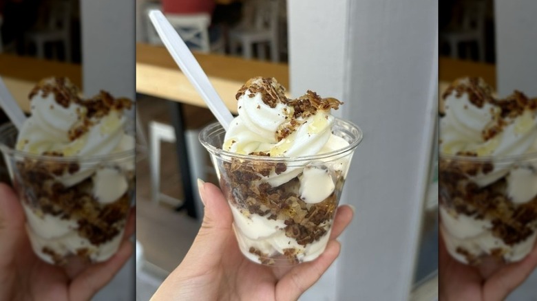 clear plastic cup of froyo with chocolate shavings and a white plastic spoon dipped in it