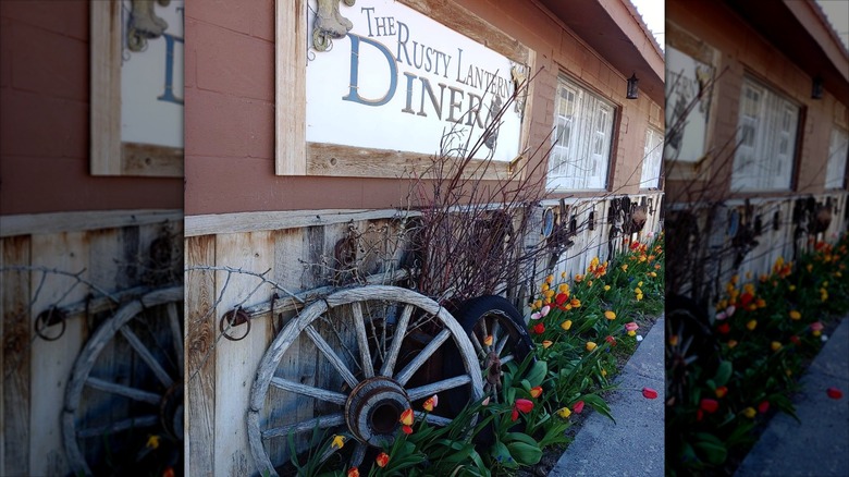 Exterior of The Rusty Lantern Diner with a rustic wagon wheel and flowers