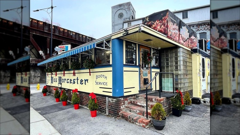 Blue and yellow exterior of Miss Worcester hole-in-the-wall restaurant with flower pots surrounding restaurant