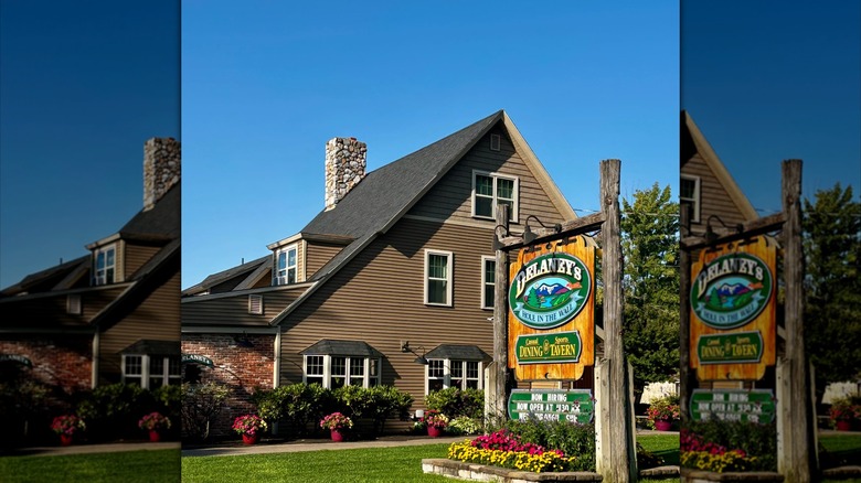 Exterior of Delaney's Hole in the Wall restaurant in big brown house with wooden sign in front yard