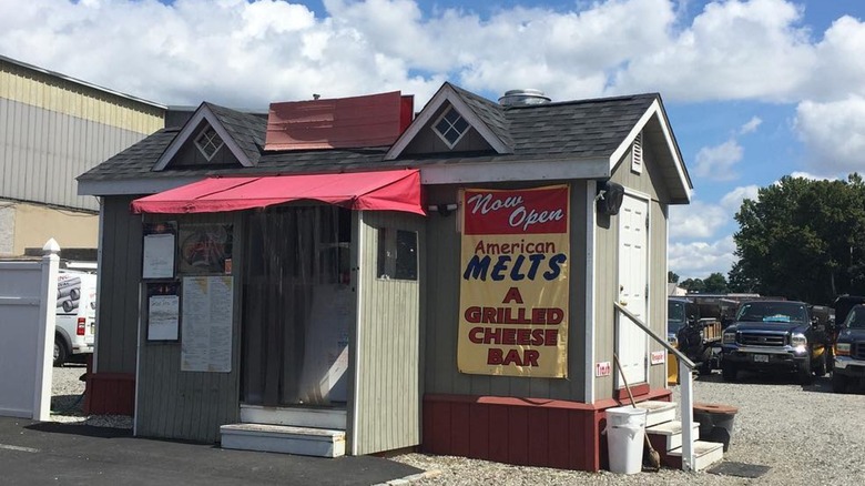 American melts hole in the wall restaurant, a small gray shack in a parking lot with yellow sign