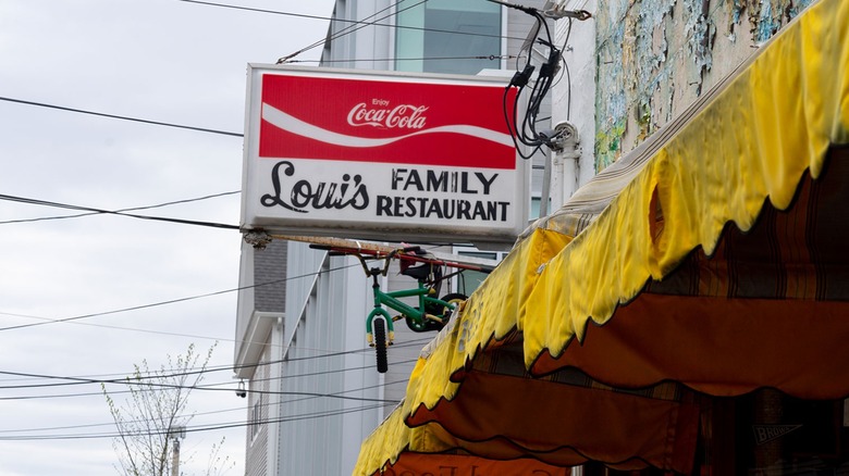 Louis family restaurant and coca-cola sign on peeling storefront