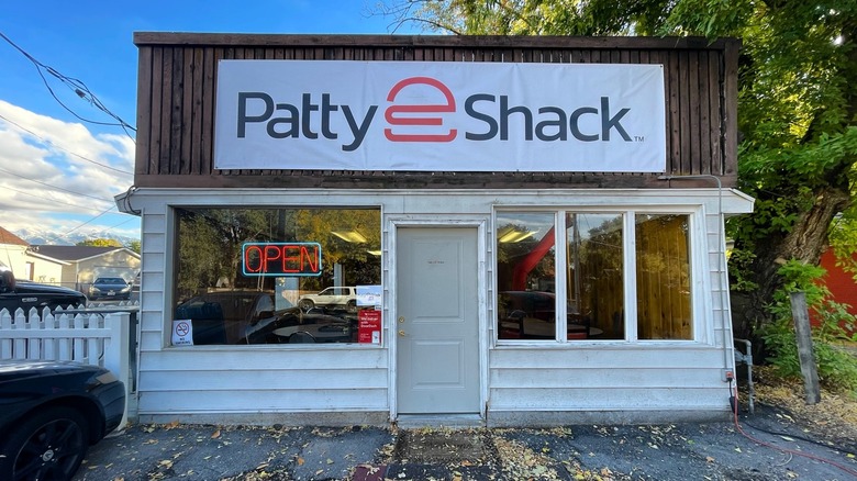 Exterior of Patty Shack a small white restaurant with neon open sign