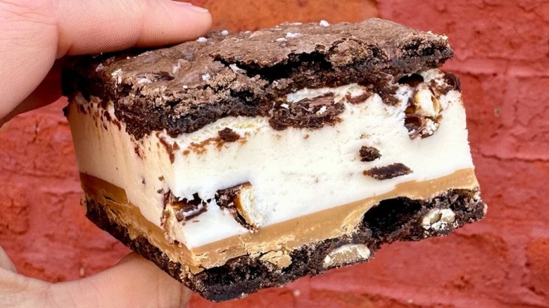 Hand holding a Sugarwitch ice cream sandwich against a brick wall