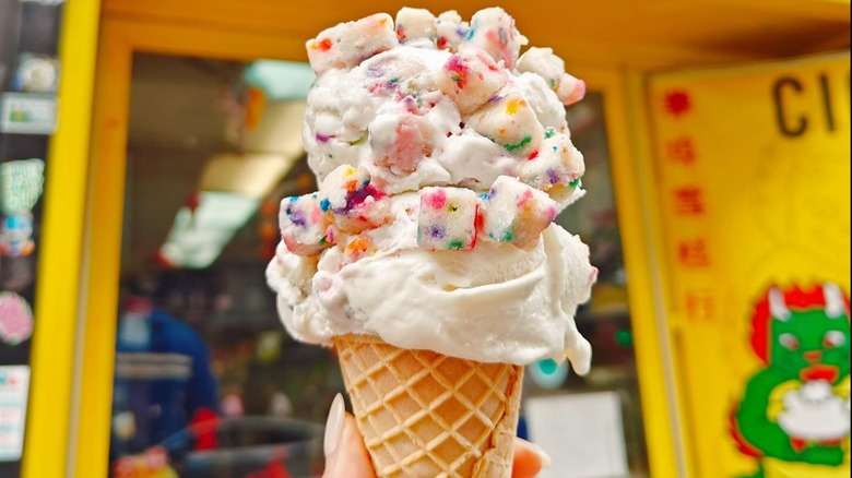 Chinatown Ice Cream Factory ice cream cone topped with marshmallow toppings and  with parlor blurred in background