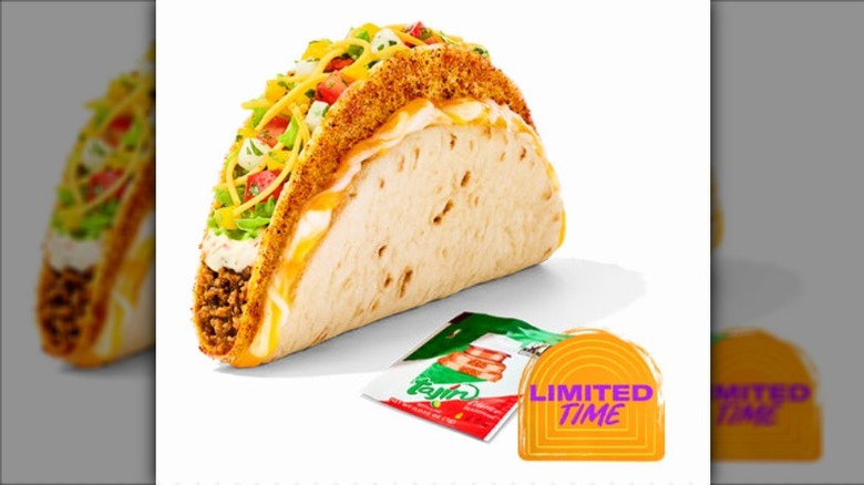 Taco Bell Tajin Cheesy Gordita Crunch with a packet of Tajin seasoning on a white background.