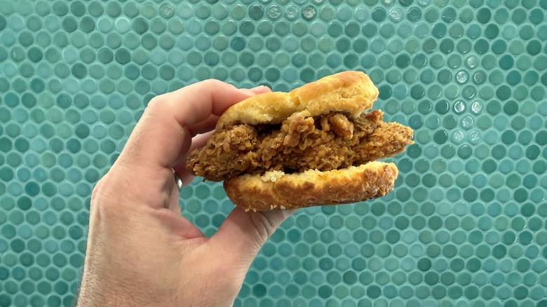 A person holding the Popeyes' Honey Chicken Biscuit in one hand