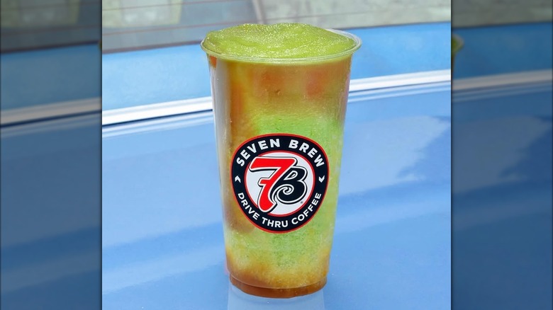 The Drizzled Apple 7 Brew Energy Frozen Chiller from 7 Brew sitting on the hood of a blue car