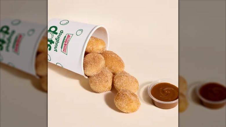 Cup with Krispy Kreme Churro Doughnut Dots spilling out and a condiment cup of dulce de lche