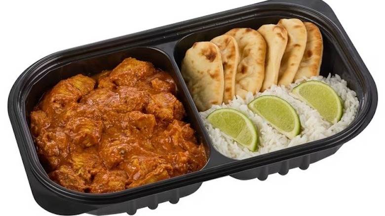 The Member's Mark Chicken Tikka Masala with rice, limes, and naan, in its black plastic tray