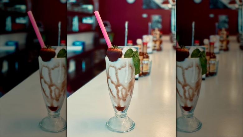 Old fashioned milkshake in tall glass with chocolate covered strawberry and pink straw at Doo-Dah Diner