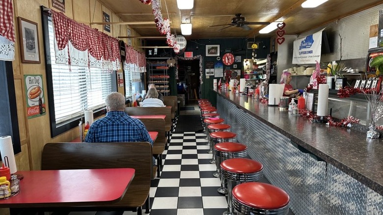 Interior with bright red counter seating and booths and black and white checkered floor at Cliffside Diner