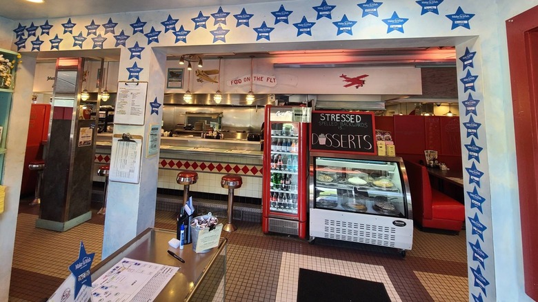 Interior dining area at Airport Diner with counter seating and glass dessert case