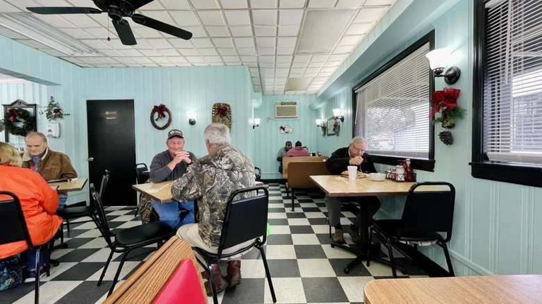 Interior dining area with black and white checkerboard floors and diners at tables at Summerton Diner