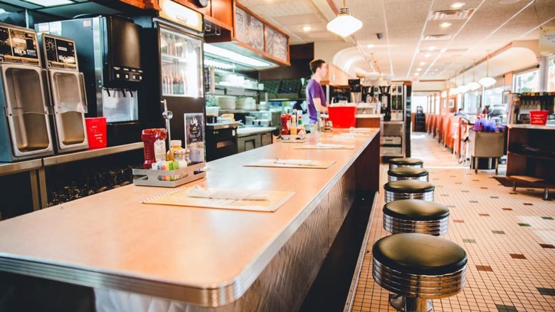 Interior dining area with counter seating and checkerboard floors at Phillips Avenue Diner