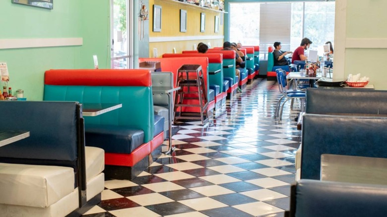 Interior dining area with vinyl multi-colored booths and checkerboard flooring at Austin Diner