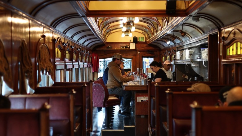 Interior of retro dining car area with counter seating and wooden interior at Frank's Diner