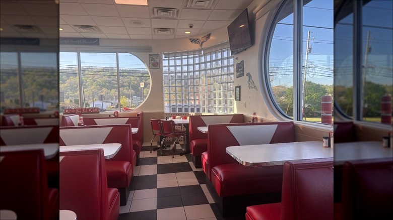 Interior dining area with black and white checkerboard flooring and bright red vinyl booths at Dolly's Diner