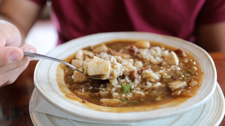 Hand shown spooning up some Mama Blue's Shrimp Gumbo in a white bowl at Bubba Gump Shrimp Co.