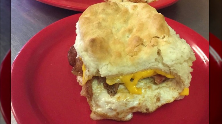 Breakfast biscuit with bacon, egg, and cheese on a red plate at Good Gravy