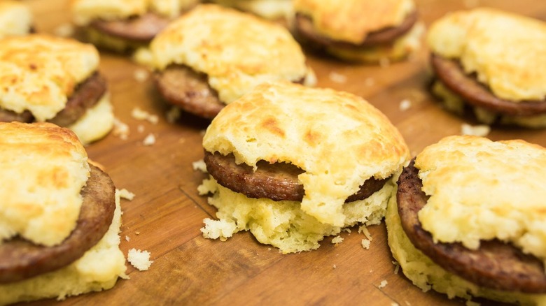Sausage biscuits lined up on wooden board