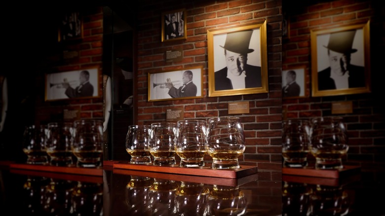 Whiskey flight on the bar at The Underground Speakeasy and Distillery with framed photos of jazz legends in the background hanging on the wall