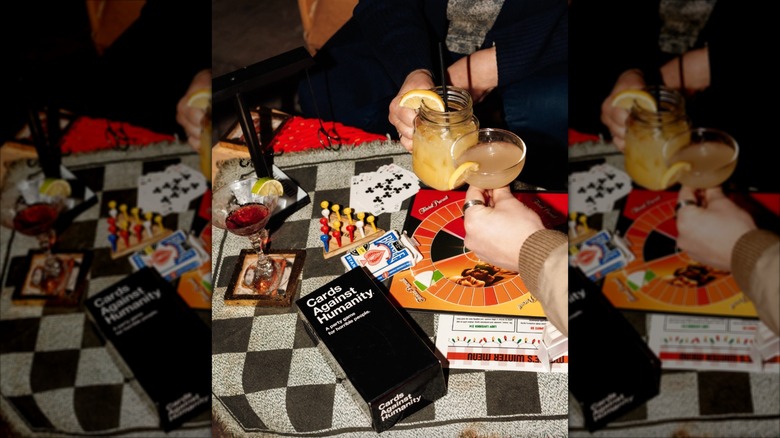 Patrons hands shown holding cocktails while playing board games at Marge's Bar