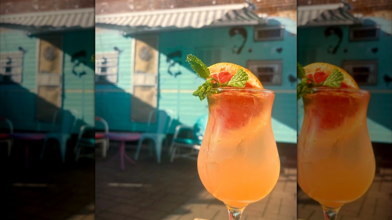 Fruity cocktail with a bright blue trailer in the background at Ogie's Trailer Park
