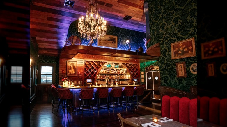 Dimly lit interior and bar area with stunning chandelier and bar seating at Honey Moon Spirit Lounge