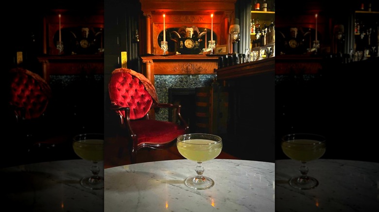 Dimly lit interior of Rosa's showing a red velvet vintage chair and cocktail on a table