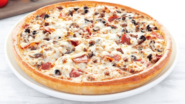 A pizza from Godfather's on a white plate sitting on a marble surface.