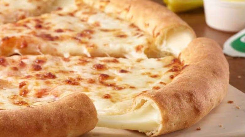 Papa John's stuffed crust cheese pizza on a table with sauces nearby.