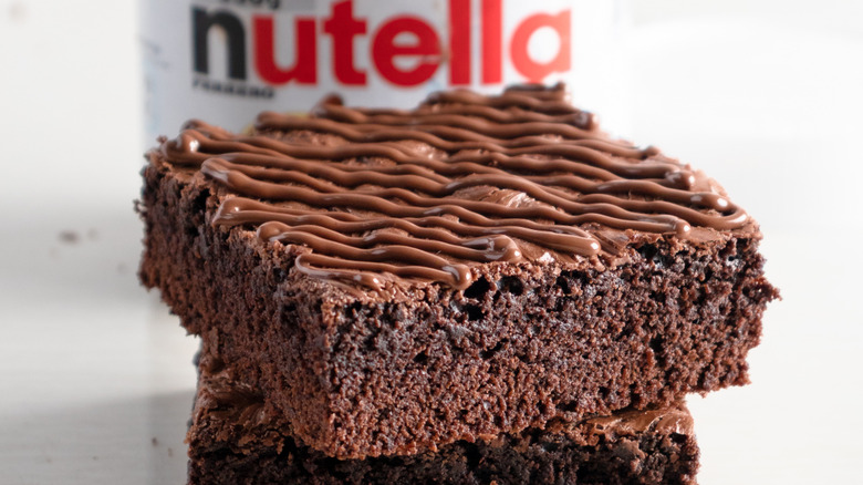 Stack of brownies with jar of Nutella in the background