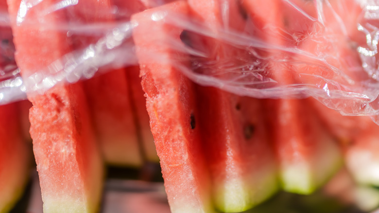 Close-up of sliced watermelon wedges covered in plastic wrap