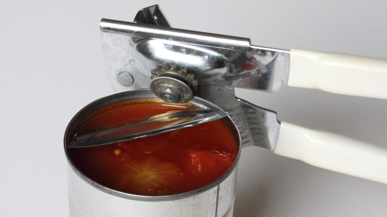 A clean can opener opens a can of tomatoes