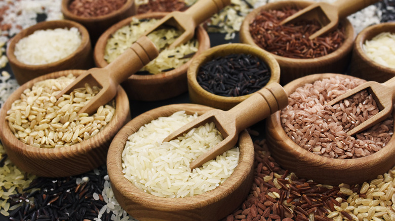 Wooden bowls filled with dried rice with wooden spoons inside